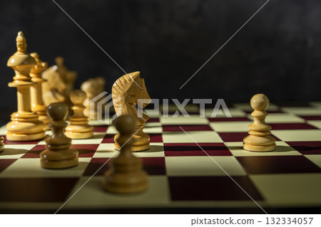 Closeup view of a white chess pawn standing against the opposing pieces on the chessboard. Concept of strategy 132334057
