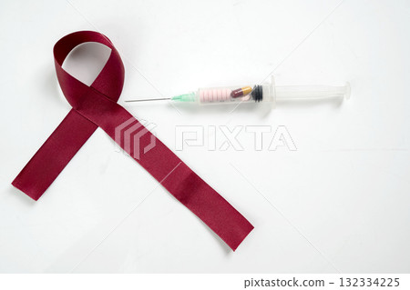Red ribbon and syringe on a white background. Symbolizing awareness and support for HIV or AIDS patients. World Aids Day. Concept of Healthcare and Medicine Red ribbon and syringe on a white background. Symbolizing awareness and support for HIV or AIDS patients. World Aids Day. Concept of Healthcare and Medicine 132334225