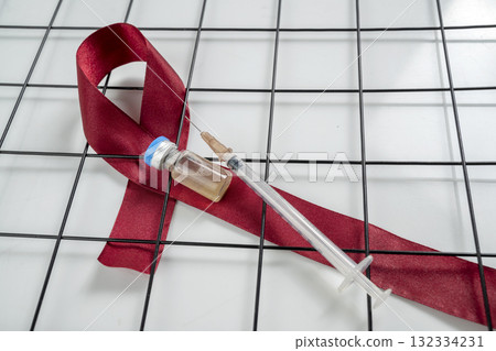 Red ribbon and syringe with vial on a white background. Symbolizing awareness and support for HIV or AIDS patients. World Aids Day. Concept of Healthcare and Medicine Red ribbon and syringe with vial on a white background. Symbolizing awareness and support for HIV or AIDS patients. World Aids Day. Concept of Healthcare and Medicine 132334231