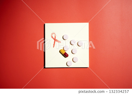 Red ribbon and medicine on a red background. Symbolizing awareness and support for HIV or AIDS patients. World Aids Day. Concept of Healthcare and Medicine 132334257