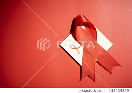 Red ribbon on a red background. Symbolizing awareness and support for HIV or AIDS patients. World Aids Day. Concept of Healthcare and Medicine Red ribbon on a red background. Symbolizing awareness and support for HIV or AIDS patients. World Aids Day. Concept of Healthcare and Medicine 132334259