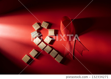Red ribbon with wooden cubes on a red background. Symbolizing awareness and support for HIV or AIDS patients. Mockup or Copy space. World Aids Day. Concept of Healthcare and Medicine Red ribbon with wooden cubes on a red background. Symbolizing awareness and support for HIV or AIDS patients. Mockup or Copy space. World Aids Day. Concept of Healthcare and Medicine 132334271