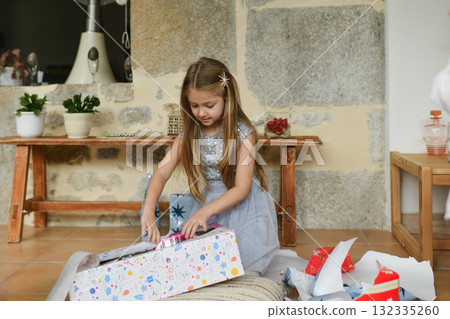 A girl unwraps the christmas presents 132335260