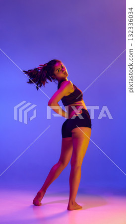 Dynamic woman in sportwear turning under neon colored light. Dynamic woman in sportwear turning under neon colored light. 132336034