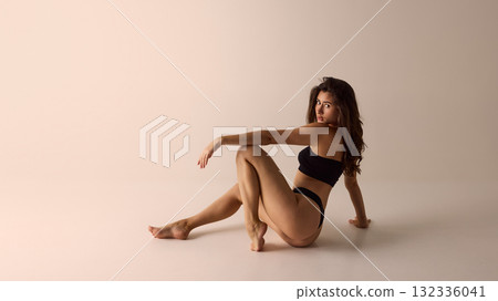 Woman in black lingerie turning back under studio light for luxury underwear campaign visuals 132336041