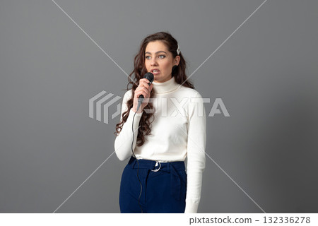 attractive female conference speaker during presentation, holds microphone and makes some gestures attractive female conference speaker during presentation, holds microphone and makes some gestures 132336278