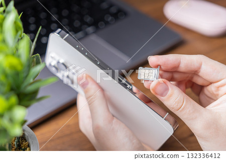 Human hands inserting a dual SIM card into a sleek white smartphone, representing essential mobile technology, global connectivity, and network activation service Human hands inserting a dual SIM card into a sleek white smartphone, representing essential mobile technology, global connectivity, and network activation service 132336412