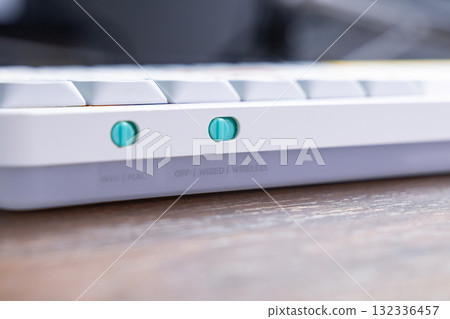 White mechanical keyboard featuring bright teal toggle switches for WIN MAC and OFF WIRED WIRELESS settings, facilitating adaptable user interface control 132336457
