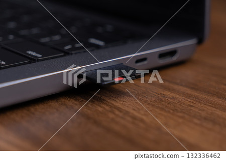 Black SD card partially inserted into a modern laptop's memory slot, representing digital data storage and efficient multimedia file transfer for technology Black SD card partially inserted into a modern laptop's memory slot, representing digital data storage and efficient multimedia file transfer for technology 132336462