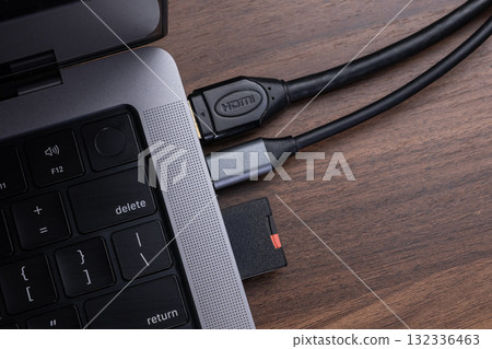 Modern laptop connected to an HDMI cable and an SD card via a versatile multi-port USB-C hub for enhanced digital connectivity and seamless data transfer 132336463