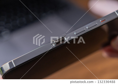 Detail of a sleek smartphone with its SIM card tray partially ejected, symbolizing essential mobile connectivity, telecommunication, and modern data technology 132336488