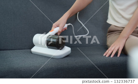 Smart Home. Woman using handheld vacuum cleaner on couch. 132336737