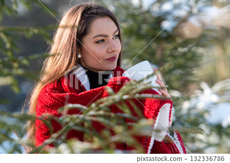 beautiful woman with a red plaid on her shoulder and a cup of tea in winter wood, winter portrait 132336786