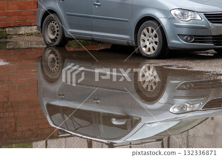 puddle on the sidewalk with a reflection of a parked car, closeup, road after rain puddle on the sidewalk with a reflection of a parked car, closeup, road after rain 132336871