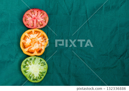 red, yellow and green tomato halves on a green background, closeup from above, abstract semaphore red, yellow and green tomato halves on a green background, closeup from above, abstract semaphore 132336886