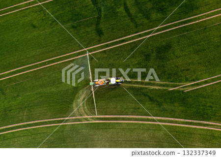 aerial view of the tractor spraying the chemicals on the large green field 132337349