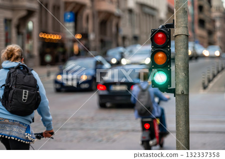 view of city traffic with traffic lights, in the foreground a semaphore with a green light, closeup 132337358