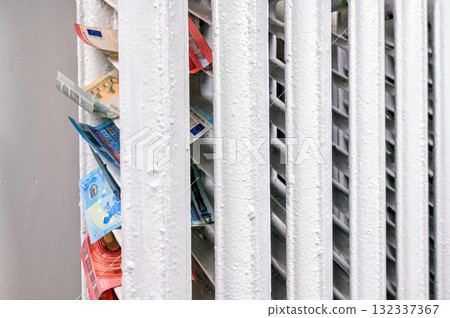euro banknotes in a central heating radiator, the concept of expensive heating costs, closeup euro banknotes in a central heating radiator, the concept of expensive heating costs, closeup 132337367