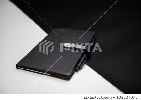 black organizer or notebook with pen on two-color black and white background, mockup, copy space 132337375
