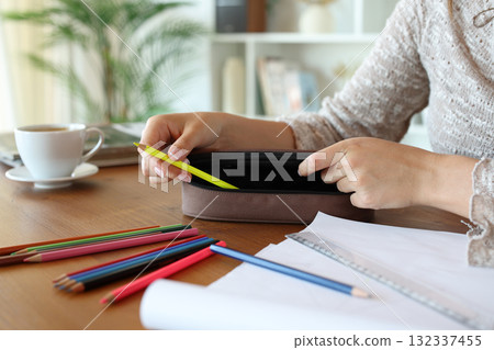 Woman hand putting pencil on case on a table Woman hand putting pencil on case on a table 132337455