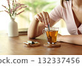 Woman hand stirring tea in a transparent cup at home 132337456
