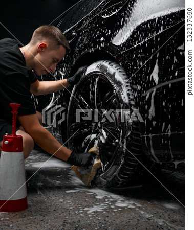 Worker cleaning car wheel with sponge during foam detailing process Worker cleaning car wheel with sponge during foam detailing process 132337690