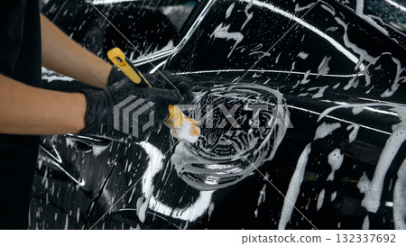 Worker cleaning fuel cap area of car with foam brush during detailing Worker cleaning fuel cap area of car with foam brush during detailing 132337692