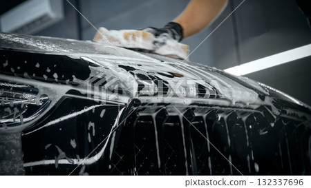 Detail shot of foam washing car front grill during detailing service 132337696