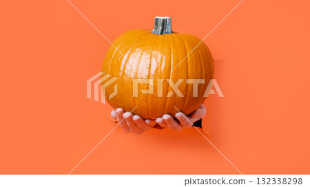Hand Holding Jack-O'-Lantern pumpkin. Hello Halloween. A hand reaches through torn orange 132338298