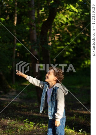 Curious boy stands under tree, gazing up with awe at birds nest. This image embodies innocence and the simple childhood joy of exploring outdoors. Curious boy stands under tree, gazing up with awe at birds nest. This image embodies innocence and the simple childhood joy of exploring outdoors. 132339129