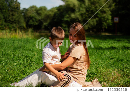 Mother with kid having fun in public green park. Happy mom laughing together with son. Quality leisure time outside Mother with kid having fun in public green park. Happy mom laughing together with son. Quality leisure time outside 132339216