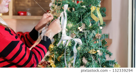 Tree Decoration. Close-up of hands adding ribbons to Christmas tree. Tree Decoration. Close-up of hands adding ribbons to Christmas tree. 132339294