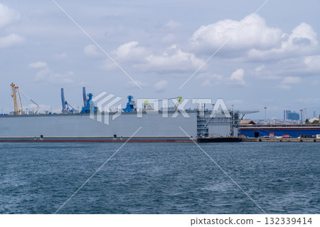 Construction of a large ship in the Bosphorus with cranes and machinery visible under a bright sky 132339414