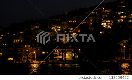 Views of illuminated homes along the shoreline of Prince Islands at night showcasing tranquil waters and lush landscapes Views of illuminated homes along the shoreline of Prince Islands at night showcasing tranquil waters and lush landscapes 132339452