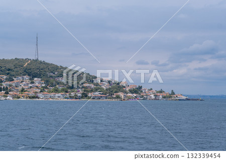 Scenic view of Prince Islands showcasing coastal residential areas and a serene sea under a cloudy sky Scenic view of Prince Islands showcasing coastal residential areas and a serene sea under a cloudy sky 132339454