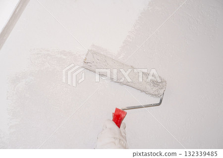 A woman manually paints a wall with a paint roller. Painting the apartment 132339485