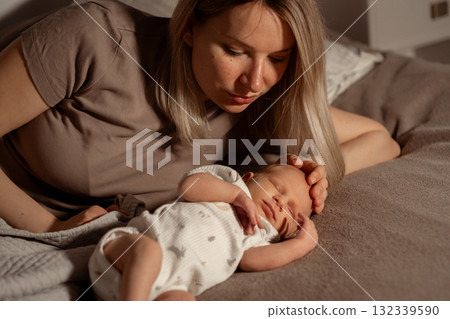 Mother gently caring for her sleeping baby at home during the evening Mother gently caring for her sleeping baby at home during the evening 132339590