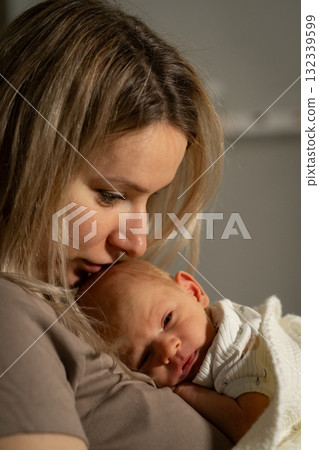 Mom holding her baby close, sharing a tender moment indoors during a cozy afternoon 132339599