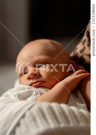 Mom lovingly cradles her newborn baby in a cozy indoor setting at night, capturing a tender moment of connection and joy 132339668