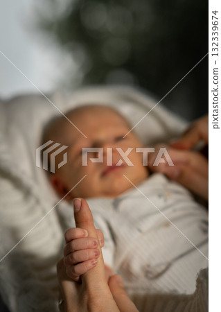 Mom gently holding her babys hand during a cozy moment outdoors in soft natural light on a calm afternoon Mom gently holding her babys hand during a cozy moment outdoors in soft natural light on a calm afternoon 132339674