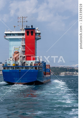 Cargo ship navigating the Bosphorus strait under a clear sky, with cityscape in the background 132339919