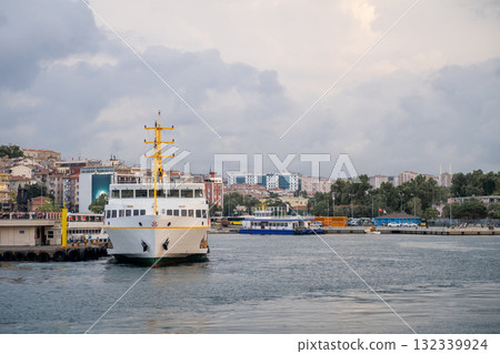 Bosphorus ferry navigating the waterway with city skyline in the background during an overcast day 132339924