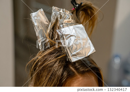 Hair coloring process in a salon using foil to create highlights for a stylish look Hair coloring process in a salon using foil to create highlights for a stylish look 132340417