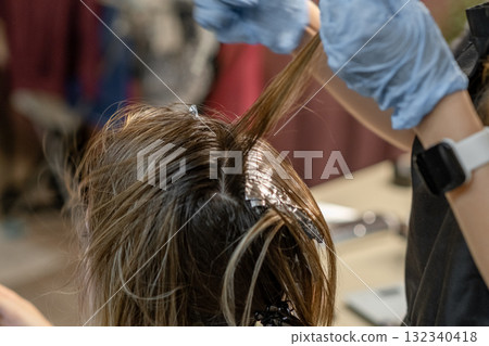 Hair coloring session in salon with stylist applying dye to clients roots in a modern setting 132340418
