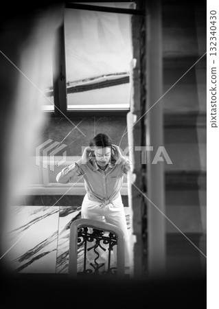Woman adjusting her hair while standing near staircase in St. Petersburg during the day 132340430