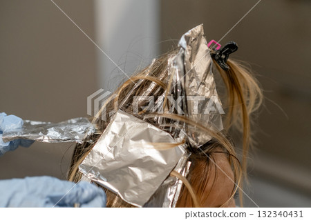Hair coloring process in a salon with foils applied for highlighting effects Hair coloring process in a salon with foils applied for highlighting effects 132340431