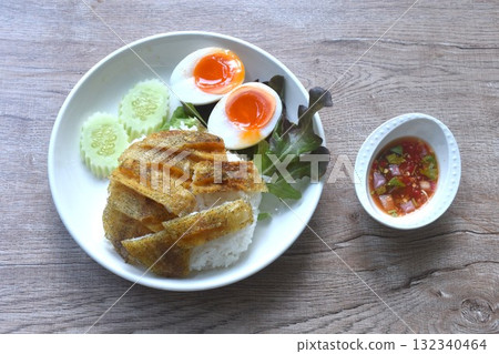 deep fried slice gourami fish topping plain rice with soft boiled egg and fresh vegetable on plate dipping spicy sweet fish sauce deep fried slice gourami fish topping plain rice with soft boiled egg and fresh vegetable on plate dipping spicy sweet fish sauce 132340464