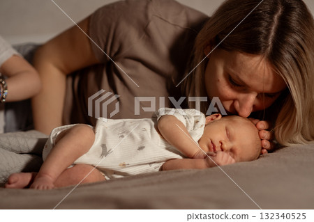 Mom cuddles her sleeping baby on a cozy bed during a quiet afternoon at home, sharing a tender moment of love and connection Mom cuddles her sleeping baby on a cozy bed during a quiet afternoon at home, sharing a tender moment of love and connection 132340525