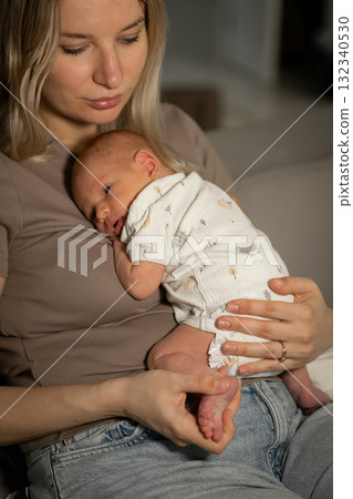Loving mom cradles her newborn baby at home during a quiet, peaceful moment in the afternoon Loving mom cradles her newborn baby at home during a quiet, peaceful moment in the afternoon 132340530