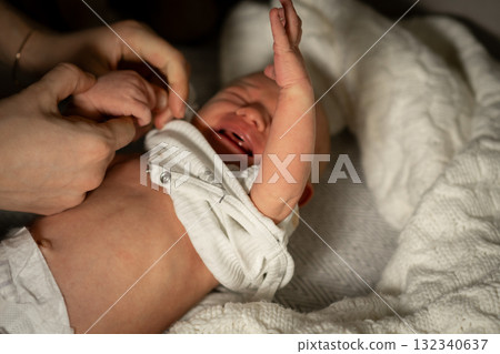 Mom caring for baby during a late-night diaper change at home in a cozy nursery setting with soft lighting 132340637
